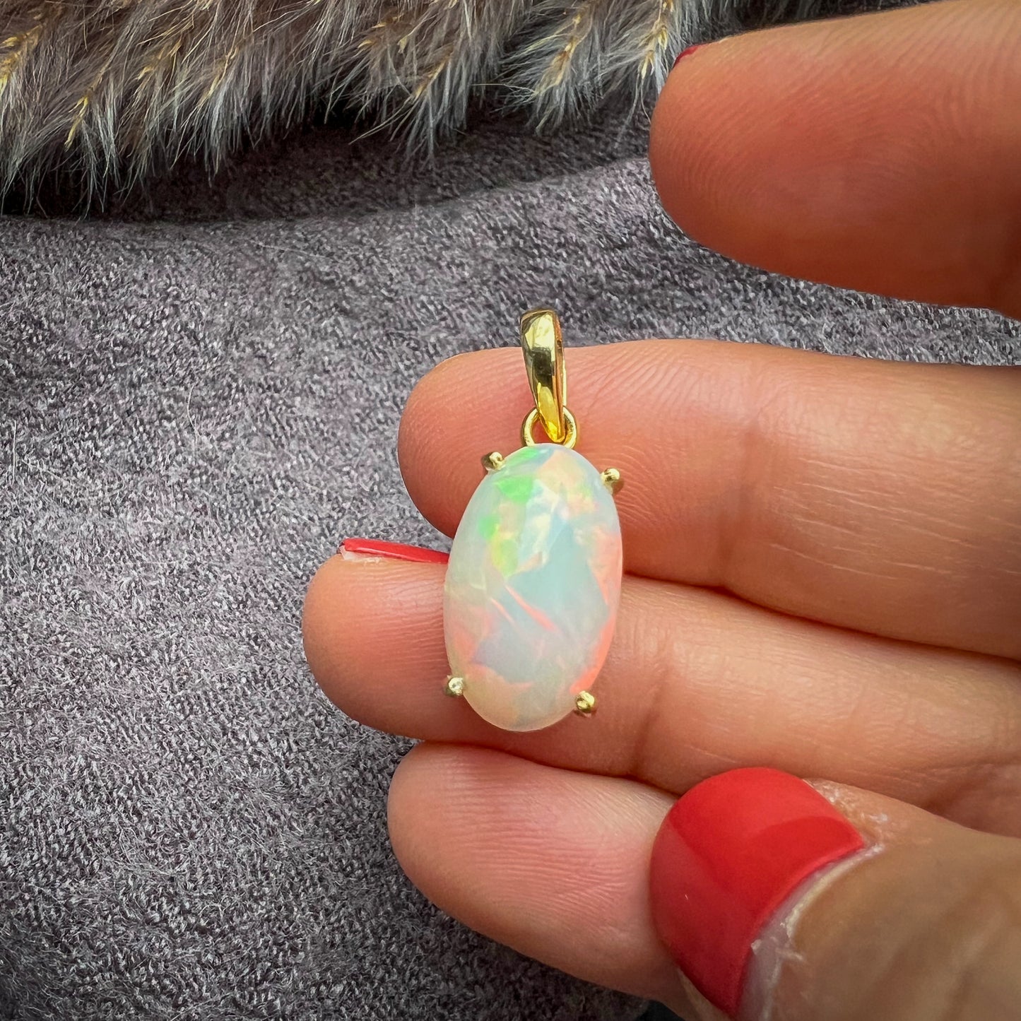 
                  
                    Ovaler Welo-Opal-Anhänger mit facettiertem Farbspiel in sanften Pastelltönen, eingefasst in eine vergoldete Silberfassung, präsentiert auf einem polierten Achat-Stein, elegantes Schmuckstück für Damen.
                  
                