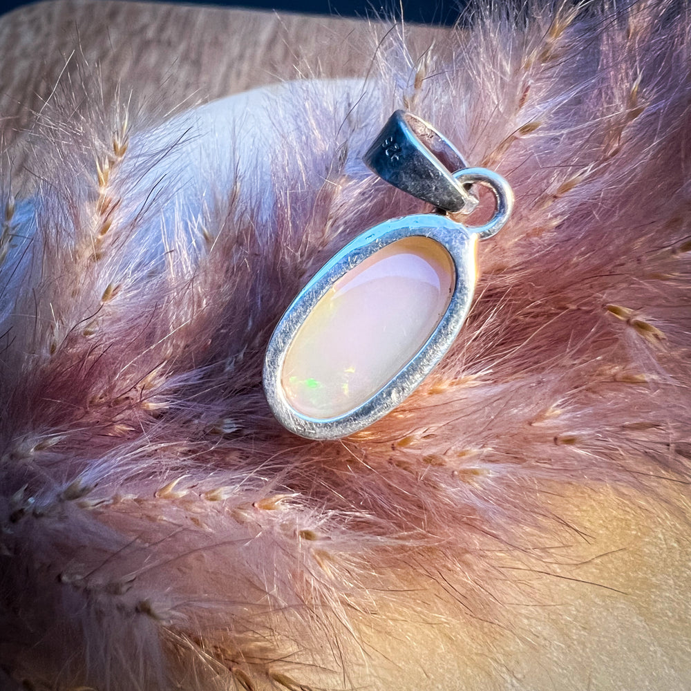 Ovaler Welo-Opal-Anhänger in sanften Pastelltönen von Rosa bis Weiß, eingefasst in eine schlichte Silberfassung, elegantes und zeitloses Schmuckstück für Damen.