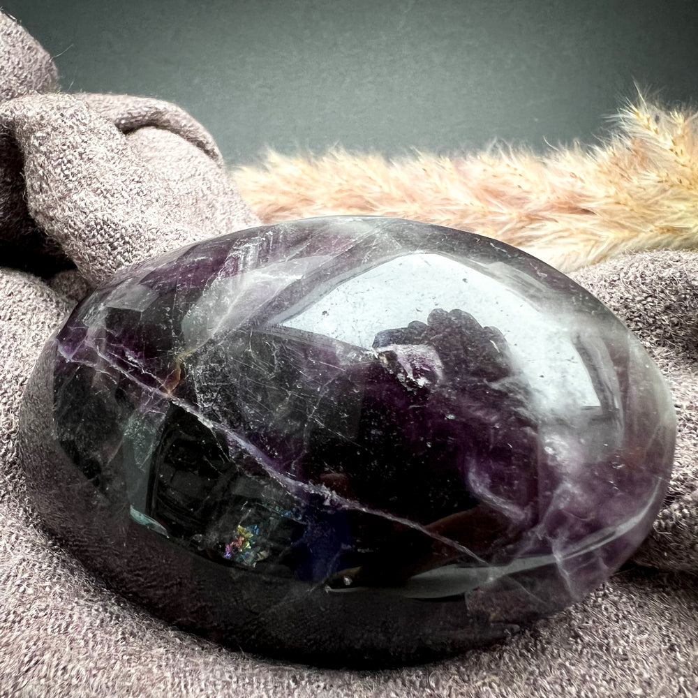 Fluorit Handschmeichler in tiefem Violett mit natürlichen Einschlüssen, glatte polierte Oberfläche, ideal als beruhigender Energiegeber für Meditation und Dekoration.