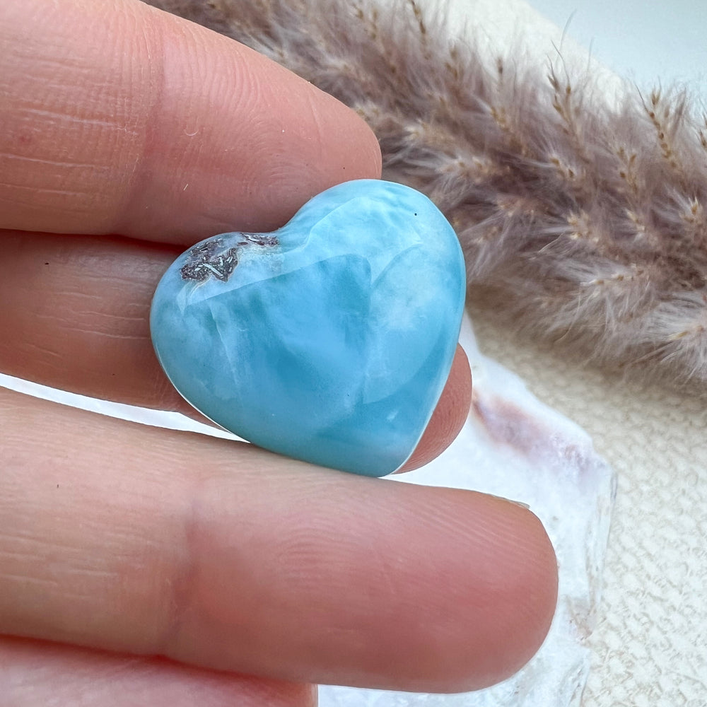 
                  
                    Kleines Larimar Herz in meeresblau mit weißen Akzenten, gehalten in der Hand, zeigt die glatte Oberfläche und einzigartige Maserung des Edelsteins.
                  
                