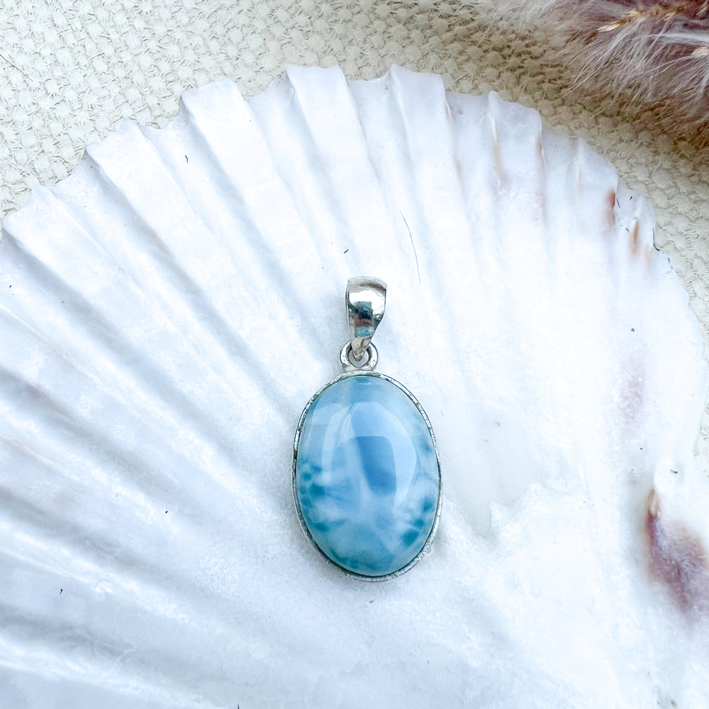 
                  
                    Ovaler Larimar-Anhänger aus 925er Sterlingsilber, Vorderseite des Steins in hellblauer Farbe mit zarten weißen Schattierungen, präsentiert auf einer Muschelschale.
                  
                