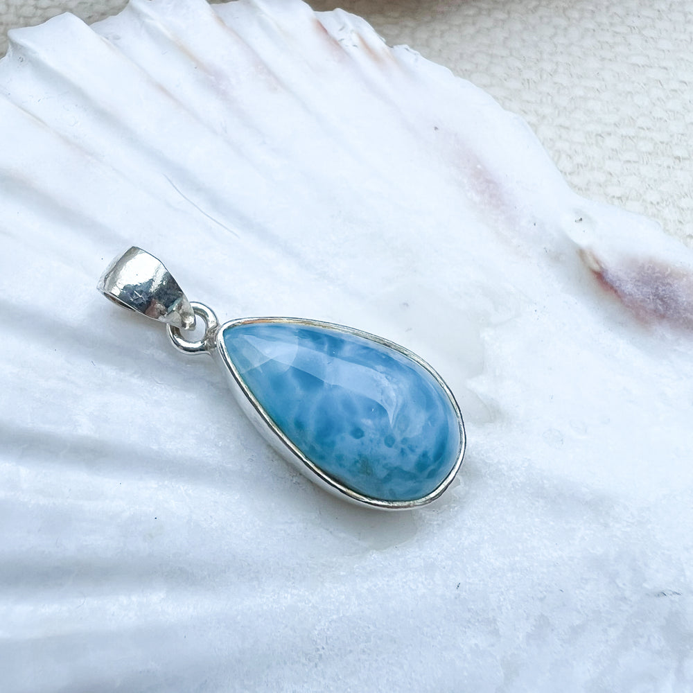 
                  
                    Larimar Tropfen-Anhänger aus 925er Sterlingsilber, präsentiert auf einer weißen Muschelschale, mit einer glatten, glänzenden Oberfläche und lebhaften Blau-Tönen
                  
                