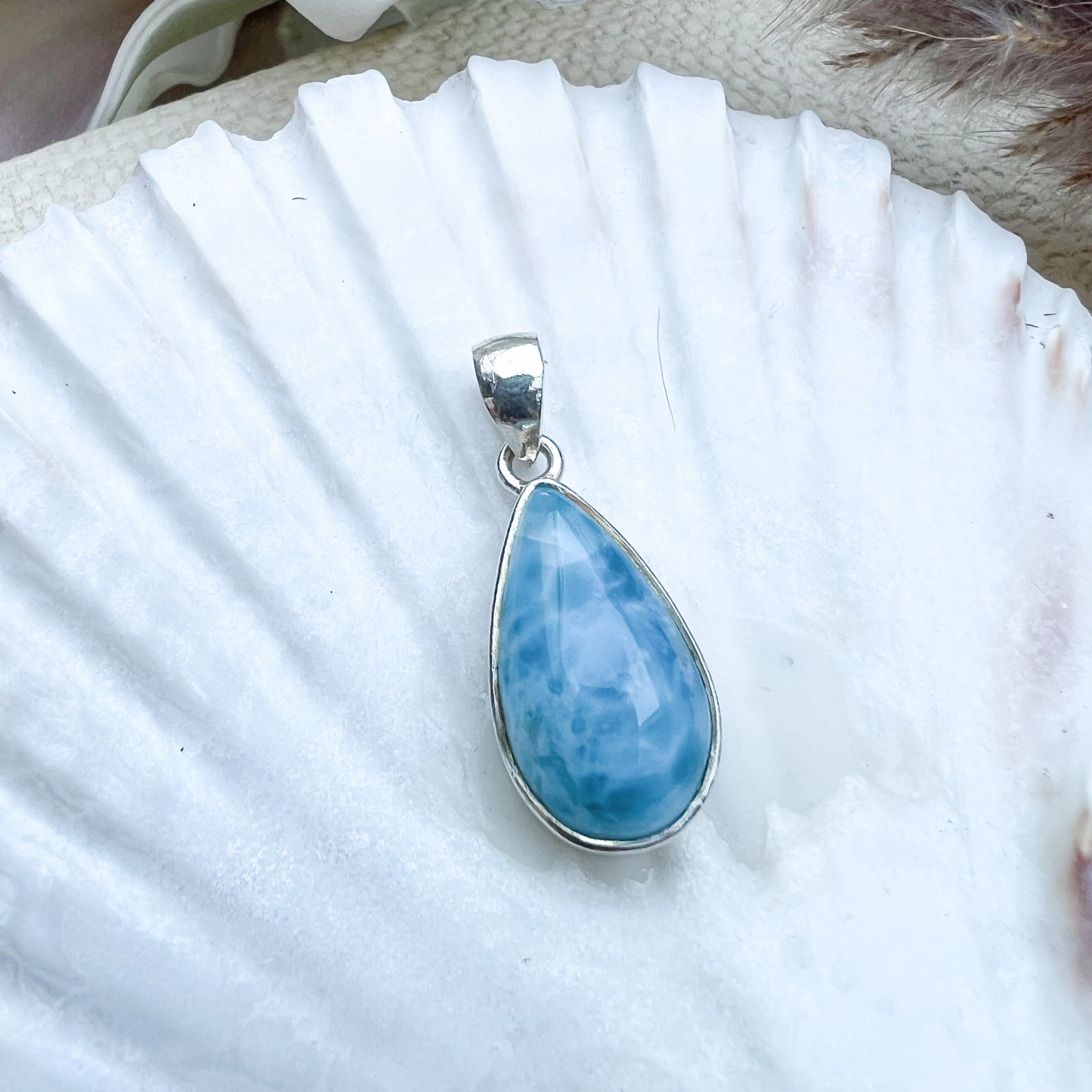 
                  
                    Larimar Tropfen-Anhänger aus 925er Sterlingsilber, präsentiert auf einer weißen Muschelschale, mit einer glatten, glänzenden Oberfläche und lebhaften Blau-Tönen
                  
                