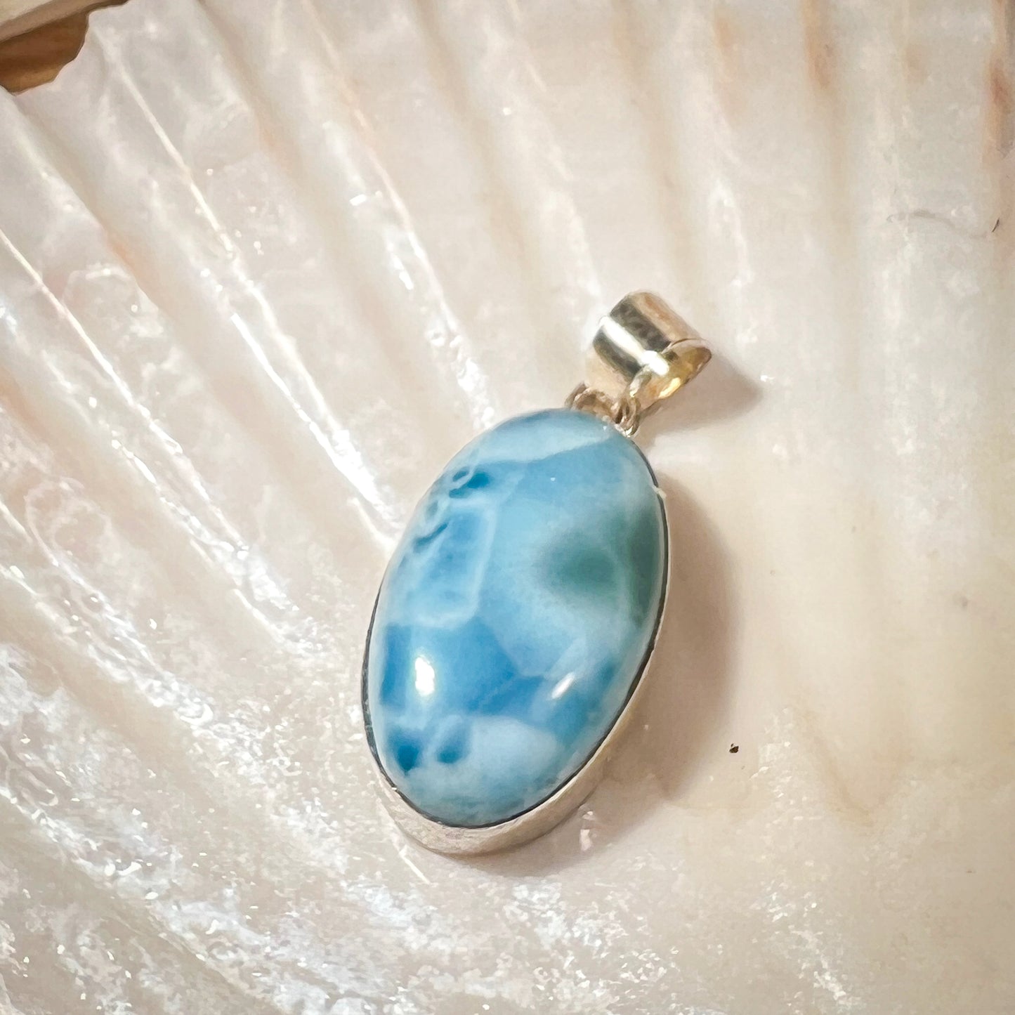 
                  
                    Ovaler Larimar-Kettenanhänger in 925er Sterlingsilber, auf einer Muschelschale präsentiert. Der blau-weiße Edelstein besticht durch natürliche Farbverläufe und erinnert an das karibische Meer. Einzigartiges Schmuckstück für Damen.
                  
                