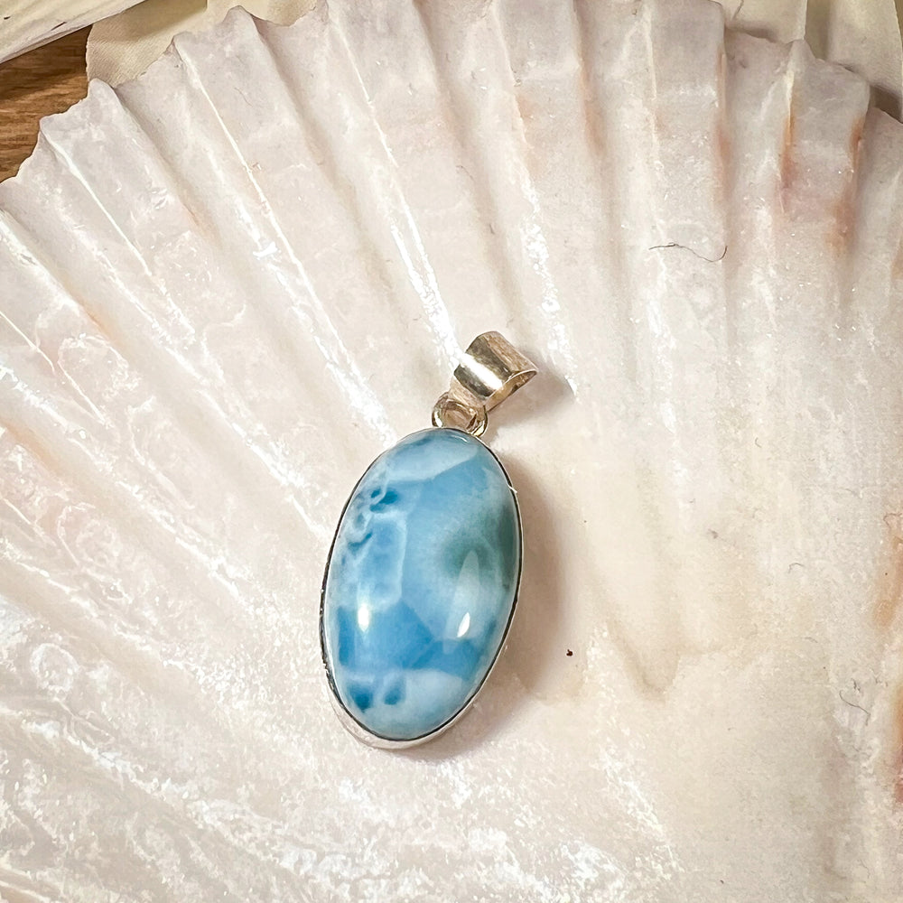 
                  
                    Ovaler Larimar-Kettenanhänger in 925er Sterlingsilber, auf einer Muschelschale präsentiert. Der blau-weiße Edelstein besticht durch natürliche Farbverläufe und erinnert an das karibische Meer. Einzigartiges Schmuckstück für Damen.
                  
                