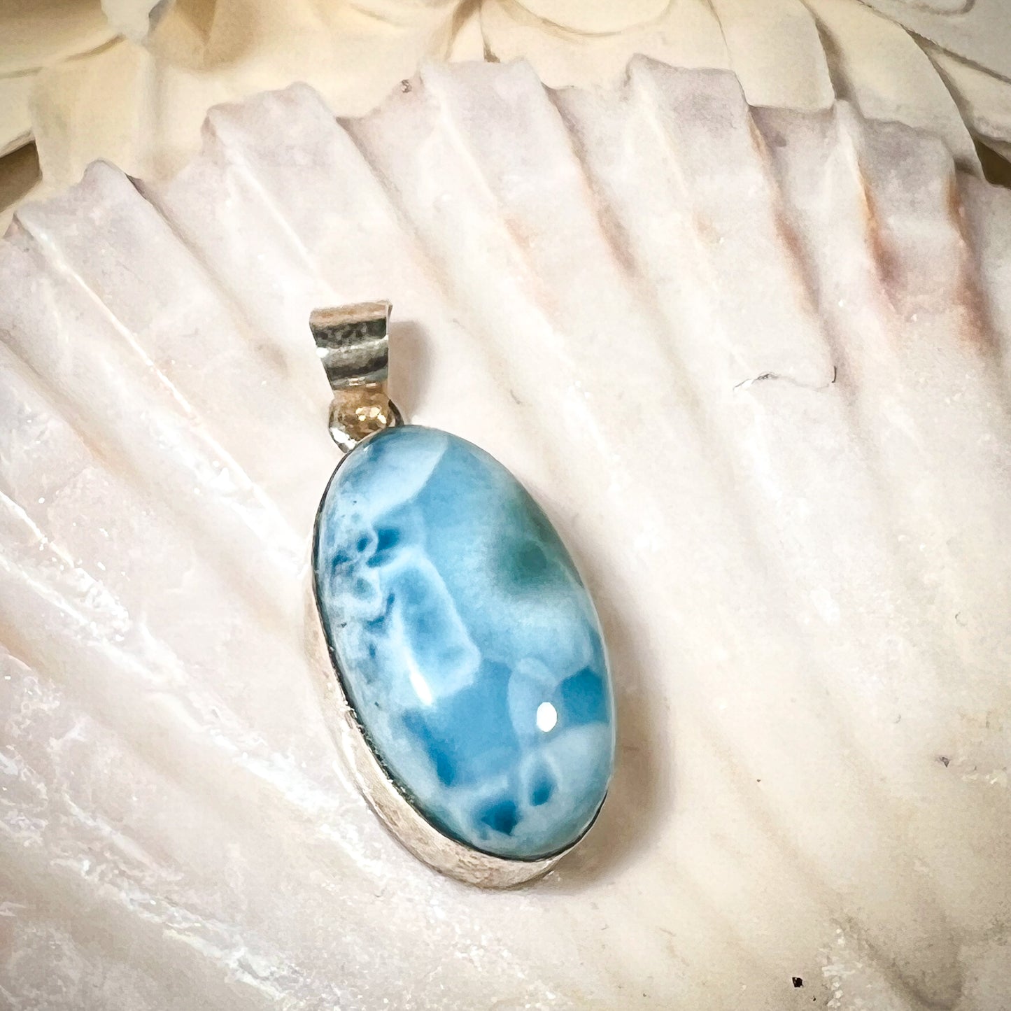 
                  
                    Ovaler Larimar-Kettenanhänger in 925er Sterlingsilber, auf einer Muschelschale präsentiert. Der blau-weiße Edelstein besticht durch natürliche Farbverläufe und erinnert an das karibische Meer. Einzigartiges Schmuckstück für Damen.
                  
                