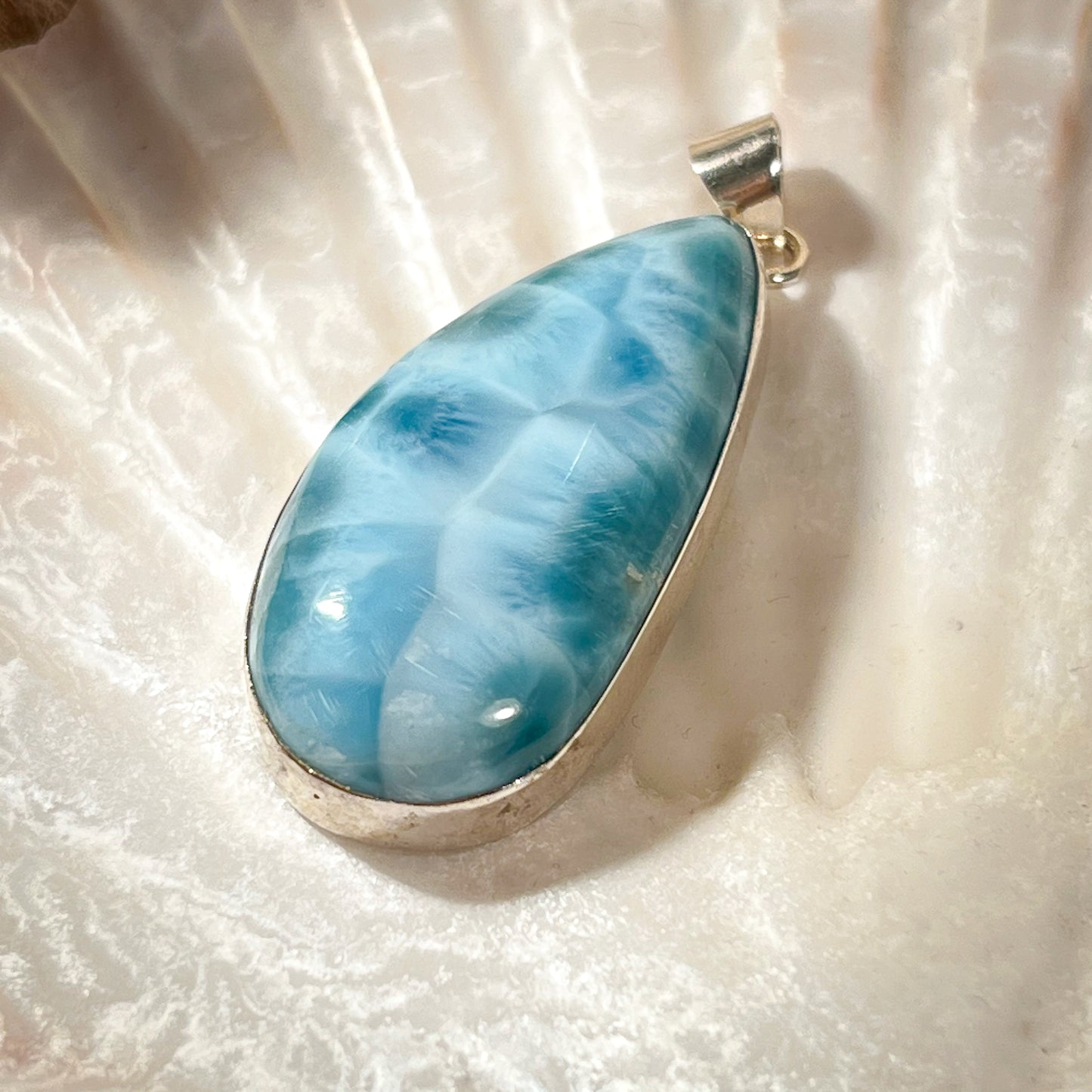 
                  
                    Eleganter Larimar-Anhänger in Tropfenform, gefasst in hochwertigem Silber, präsentiert auf einer Muschelschale. Der hellblaue Edelstein mit natürlicher Maserung wirkt beruhigend und erinnert an die Farben des Meeres. Ideal als einzigartiges Schmuckstück für spirituelle und modebewusste Träger. Hochwertiger Larimar-Anhänger für Damen, perfekt als Geschenk oder für besondere Anlässe.
                  
                