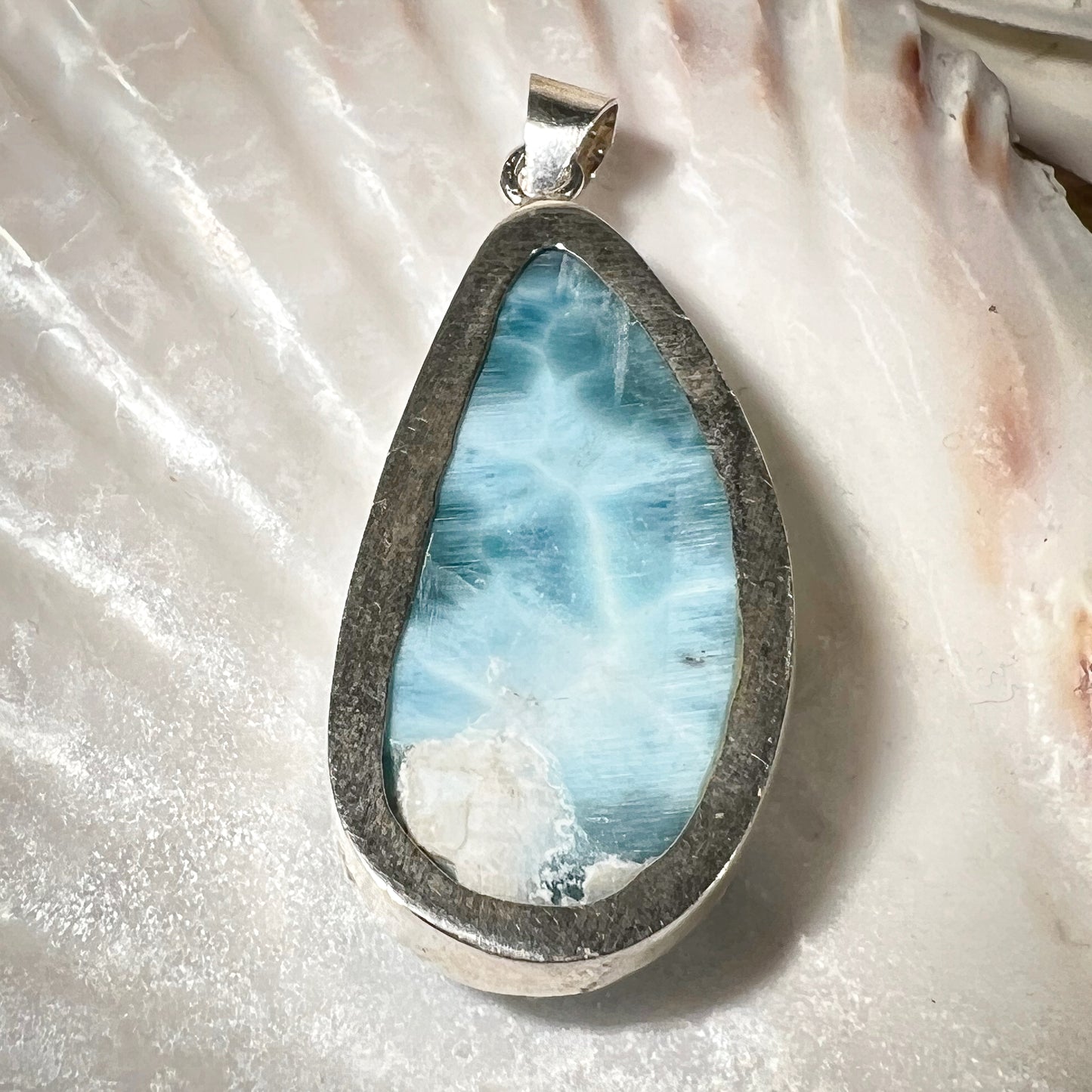 
                  
                    Eleganter Larimar-Anhänger in Tropfenform, gefasst in hochwertigem Silber, präsentiert auf einer Muschelschale. Der hellblaue Edelstein mit natürlicher Maserung wirkt beruhigend und erinnert an die Farben des Meeres. Ideal als einzigartiges Schmuckstück für spirituelle und modebewusste Träger. Hochwertiger Larimar-Anhänger für Damen, perfekt als Geschenk oder für besondere Anlässe.
                  
                