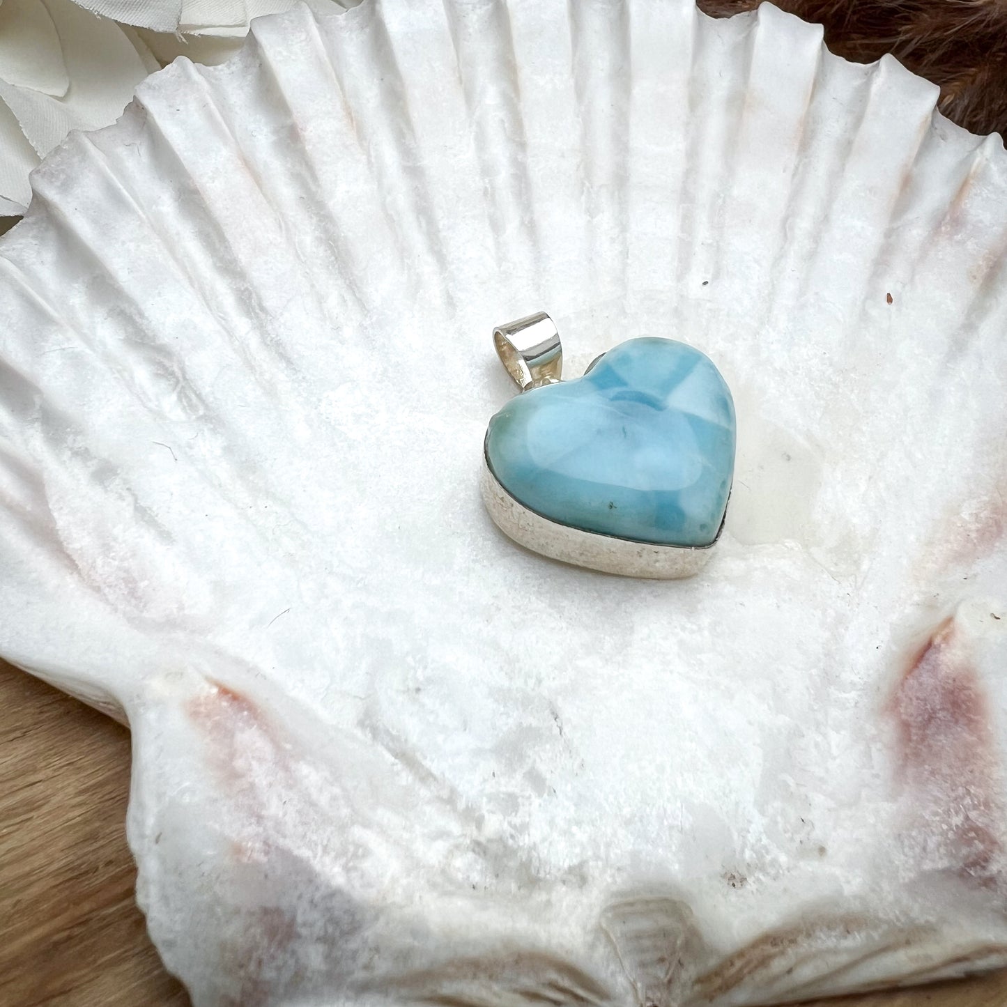 
                  
                    Herzförmiger Larimar-Kettenanhänger in 925er Sterlingsilber auf Muschelschale. Der blau-weiße Edelstein zeigt natürliche Muster und erinnert an das karibische Meer. Elegantes Unikat und perfektes Geschenk für Damen.
                  
                