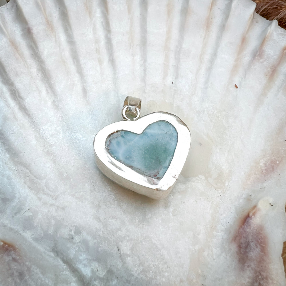 
                  
                    Herzförmiger Larimar-Kettenanhänger in 925er Sterlingsilber auf Muschelschale. Der blau-weiße Edelstein zeigt natürliche Muster und erinnert an das karibische Meer. Elegantes Unikat und perfektes Geschenk für Damen.
                  
                