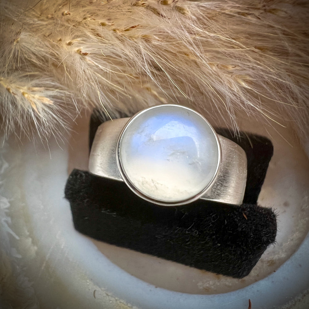 Breiter Silberring mit natürlichem ovalem Mondstein, geheimnisvoll schimmernde Blau- und Weißtöne, elegantes und zeitloses Schmuckdesign, hochwertiger Mondsteinring für Damen.